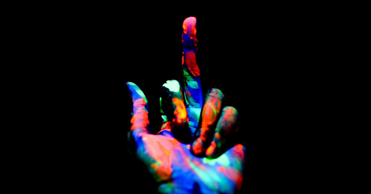 GoWipe gone wrong - Crop anonymous persons hand painted with multicolored bright neon colors showing middle finger in obscurity