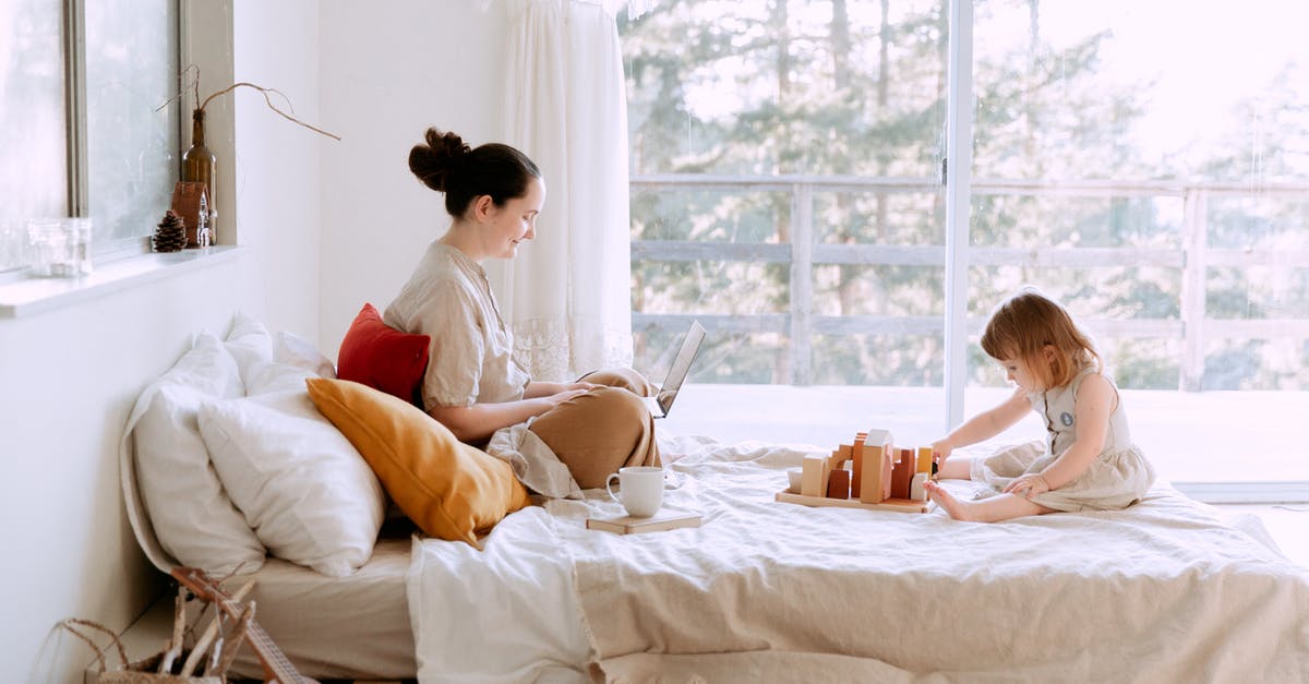 GTA 4 PC - Can't login to Windows account for online play - Full body of happy mother surfing netbook and daughter playing with toys on bed against window