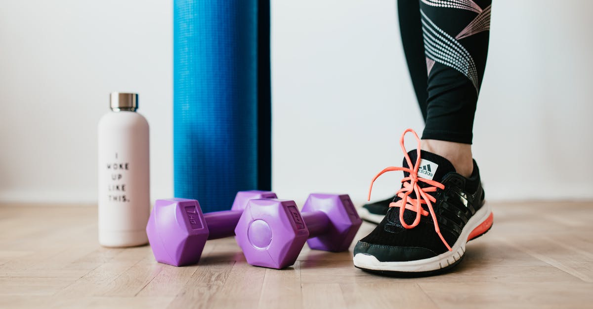 Gta 5 hobbies & pastimes - Crop sportswoman wearing sneakers and black leggings standing with sport mat on wooden floor near dumbbells and water bottle before exercising indoors