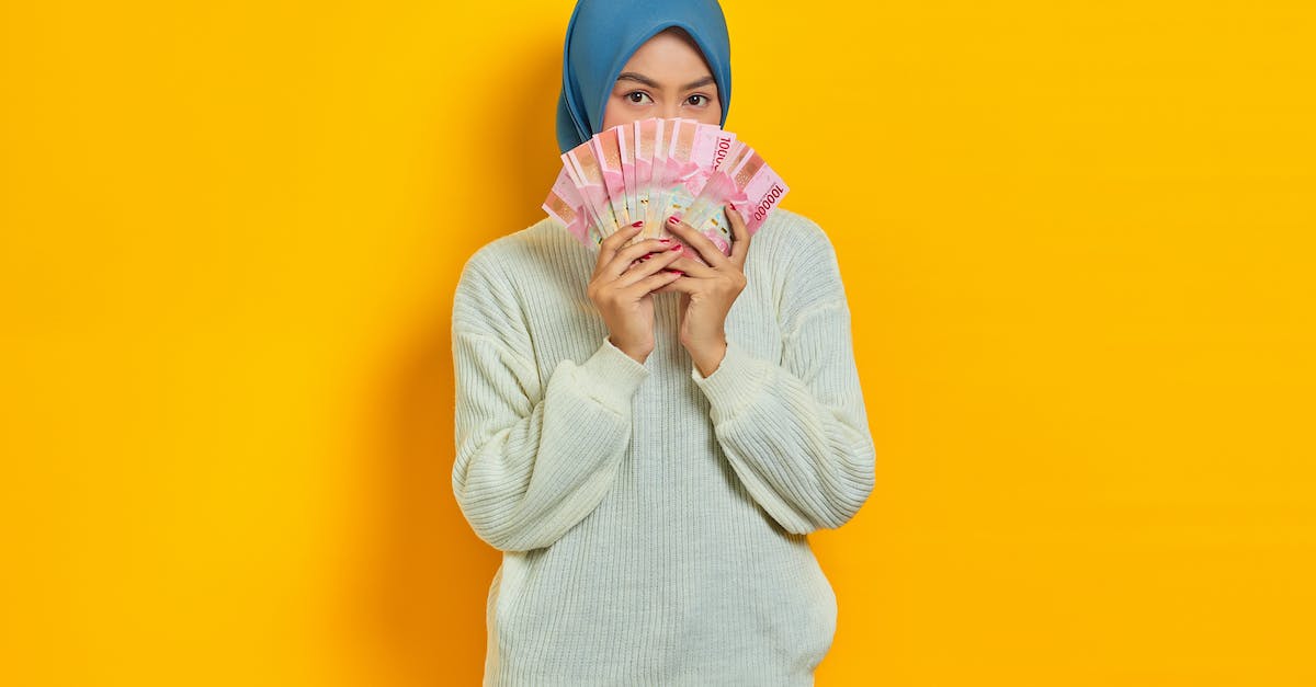 Gta V final mission not showing - Beautiful Asian Muslim woman in white sweater covering face with cash money in Indonesian rupiah banknotes isolated over yellow background. People religious lifestyle concept Gta V final mission not showing - Beautiful Asian Muslim woman in white sweater covering face with cash money in Indonesian rupiah banknotes isolated over yellow background. People religious lifestyle concept