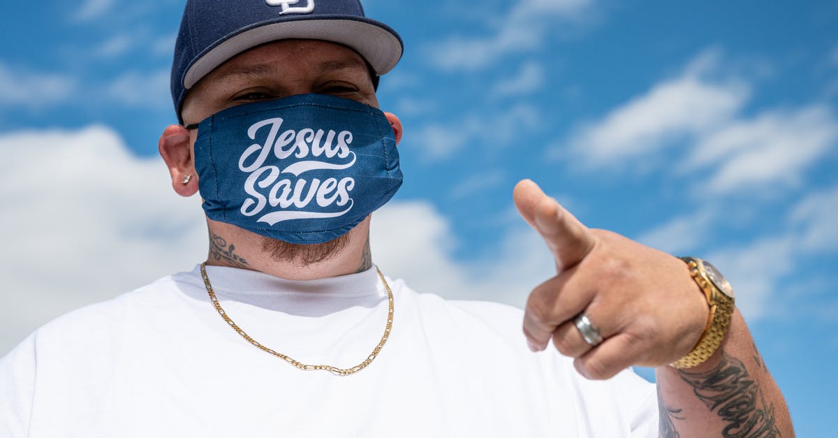 Gwent Chain Medic Revives? - Ethnic man with tattoos in white t shirt and cap and protective mask with Jesus Saves inscription pointing finger at camera Gwent Chain Medic Revives? - Ethnic man with tattoos in white t shirt and cap and protective mask with Jesus Saves inscription pointing finger at camera