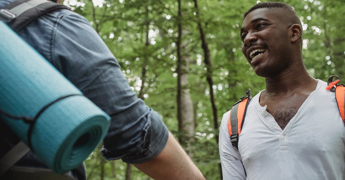 Hay day revive others' tree - Cheerful young black male in white shirt looking at anonymous friend in forest in daytime on blurred background