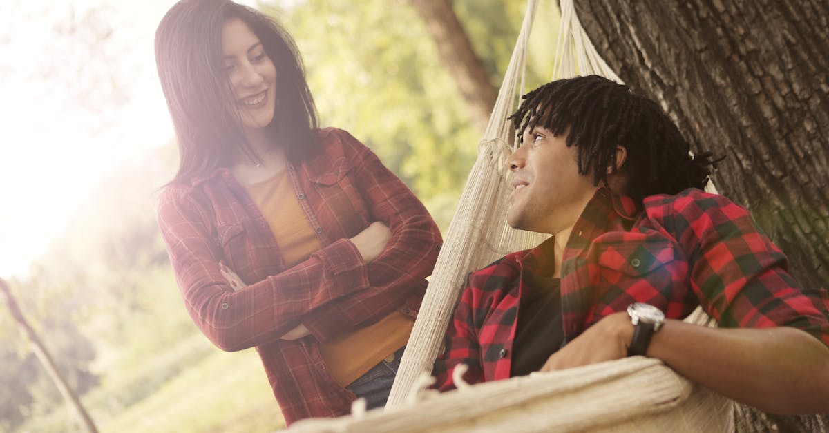 Hay day revive others' tree - Cheerful young woman with crossed arms standing next to ethnic friend while man lying on hammock in park