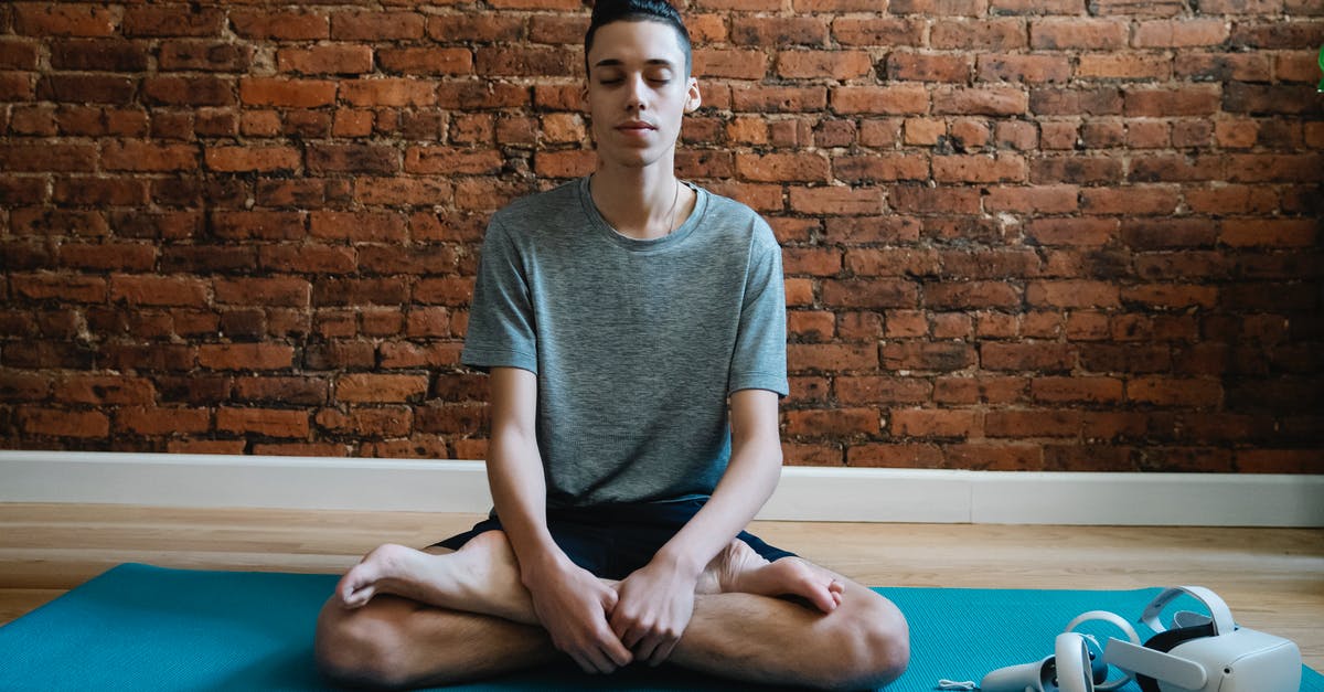 Headset Cross Compatibility for PS4 and X1 - Full body of focused male teenager in activewear meditating in lotus pose on mat near VR glasses