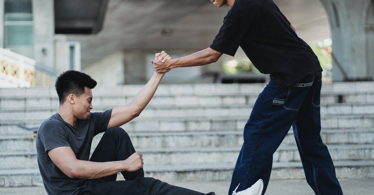 Help my friend leave his invisible clan? - Asian man helping friend to get up from ground