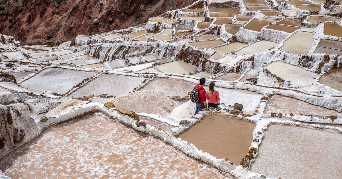 How are Visiting and Domestic tourists calculated? - Man in Red Jacket Sitting on Brown Rock Formation