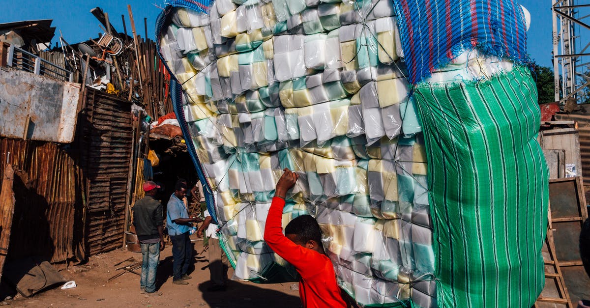How big is a stack? - Side view of anonymous ethnic male in casual wear carrying heavy stack of merchandise with striped bags on dry terrain under blue sky in sunlight How big is a stack? - Side view of anonymous ethnic male in casual wear carrying heavy stack of merchandise with striped bags on dry terrain under blue sky in sunlight
