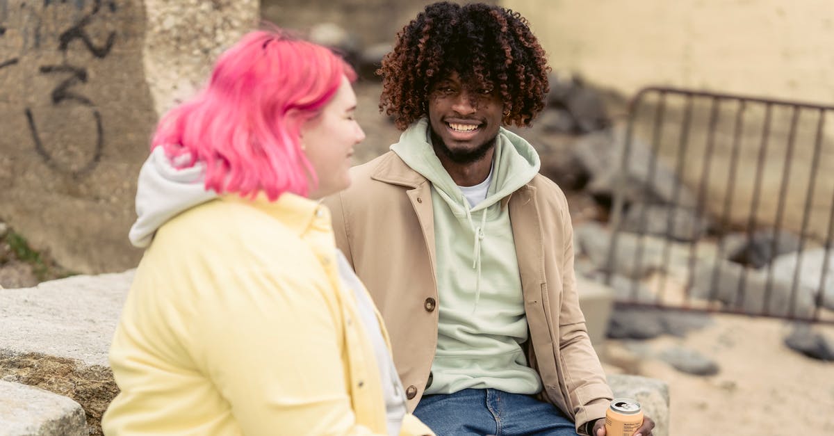 How can I backup the realm after expiry date? [duplicate] - Cheerful multiracial couple with cans of soda sitting on stones on embankment near river while spending time together during date