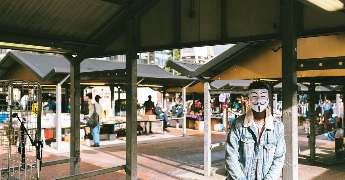 How can I change my character's appearance after starting Pokémon GO? - Unrecognizable black man in stylish clothes and Anonymous mask standing in local market in city and looking at camera in sunny day
