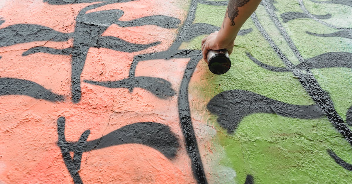 How can I change my worlds from Survival to Creative? - From below of crop anonymous talented painter with tattoo spraying paint on wall with colorful patterns on street in city