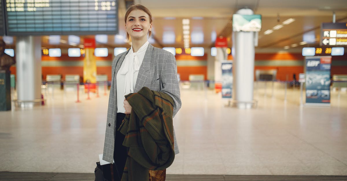 How can I check my framerate in Microsoft Flight Simulator? - Happy young woman standing with baggage near departure board in airport