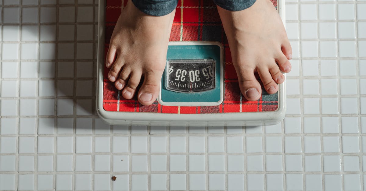 How can I control the Romances in Mass Effect 2? - From above crop anonymous barefoot child in jeans standing on weigh scales on tiled floor of bathroom
