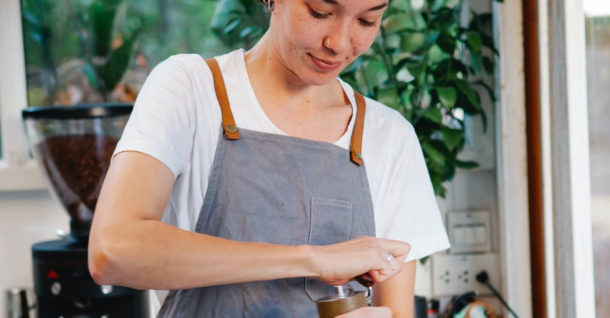 How can I create a shop with currency in Minecraft, using the scoreboard command? [duplicate] - Crop happy female in apron smiling and using grinder for preparing aromatic coffee in kitchen