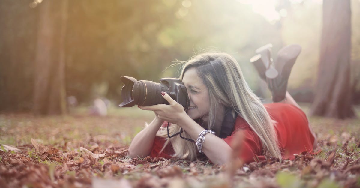 How can I detect if a person takes fall damage? - Smiling woman taking photos on professional photo camera in forest How can I detect if a person takes fall damage? - Smiling woman taking photos on professional photo camera in forest