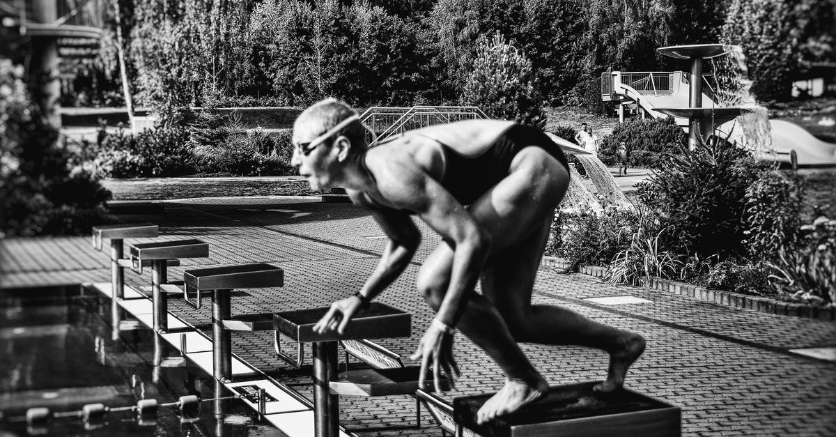 How can I determine the bottleneck for block lag? - Black and white side view full body sporty swimmer in swimming suit and goggles standing on block in track start position preparing to dive in outside pool