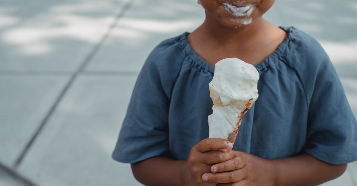How can I eat in peaceful mode? - Little child with dirty mouth standing with ice cream on street