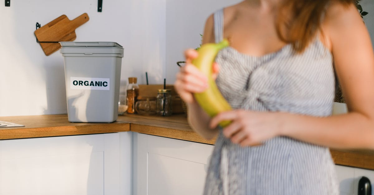 How can I get more snacks? - Crop woman with organic banana in hands standing in kitchen