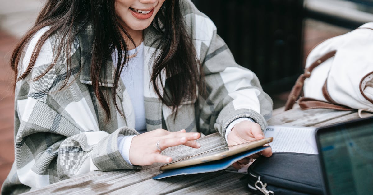 How can I get the elder scroll dialogue from the orc in the college? - High angle of happy young Asian female student working on tablet while doing home task sitting at table in campus