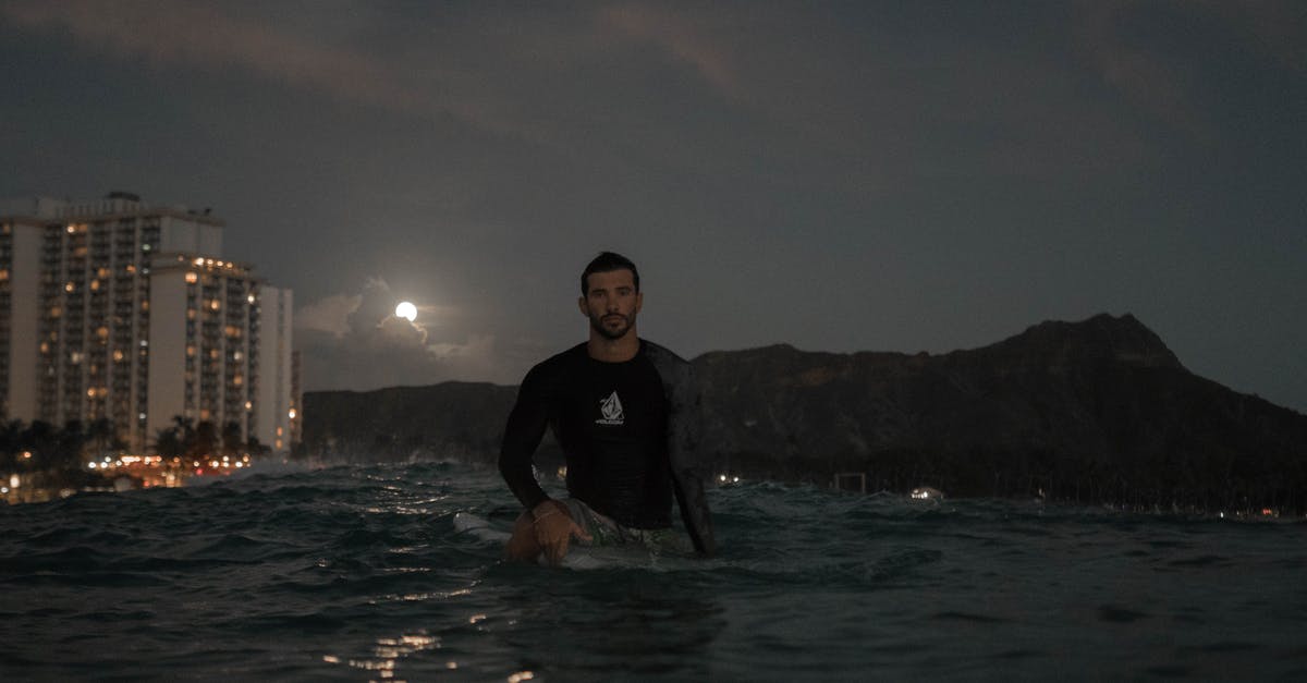 How can I get to the last wave of the pumpkin Moon in terraria 1.2.3 console? [duplicate] - Young bearded male surfer in wetsuit standing in sea water near coastlines with illuminated buildings against night sky