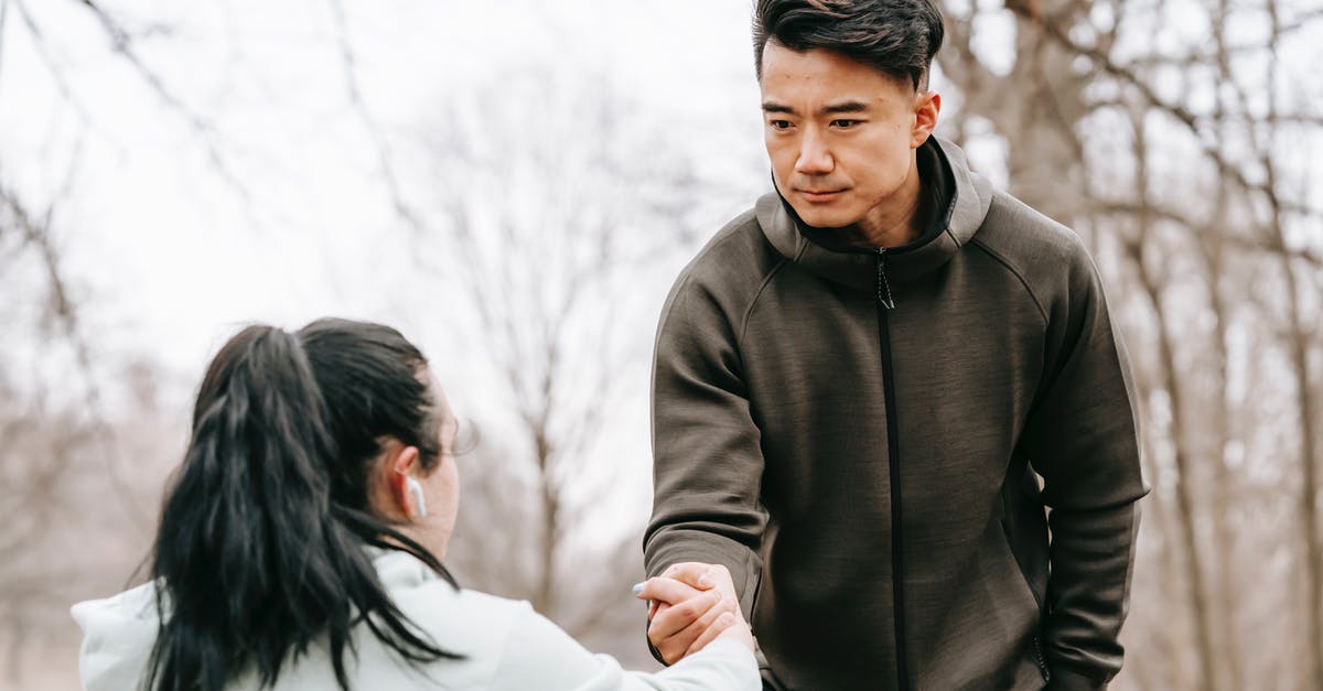 How can I give my friend one of my world saves in Terraria? - Calm Asian man in sportswear giving hand to unrecognizable female with dark hair in earphones in autumn park in daytime