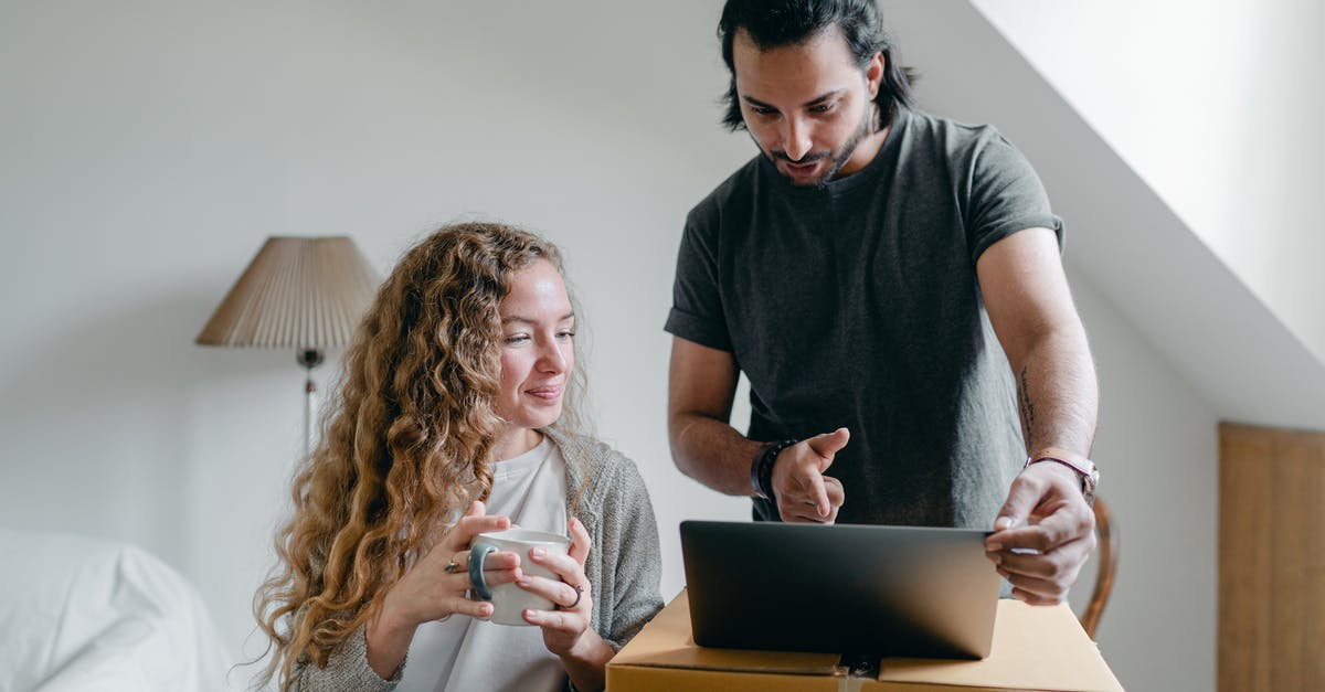 How can I migrate The Sims 3 Expansion Packs and Stuff Packs games from my old laptop to a new computer? - Positive happy young couple in casual clothes packing belongings into carton box and using laptop in living room near window