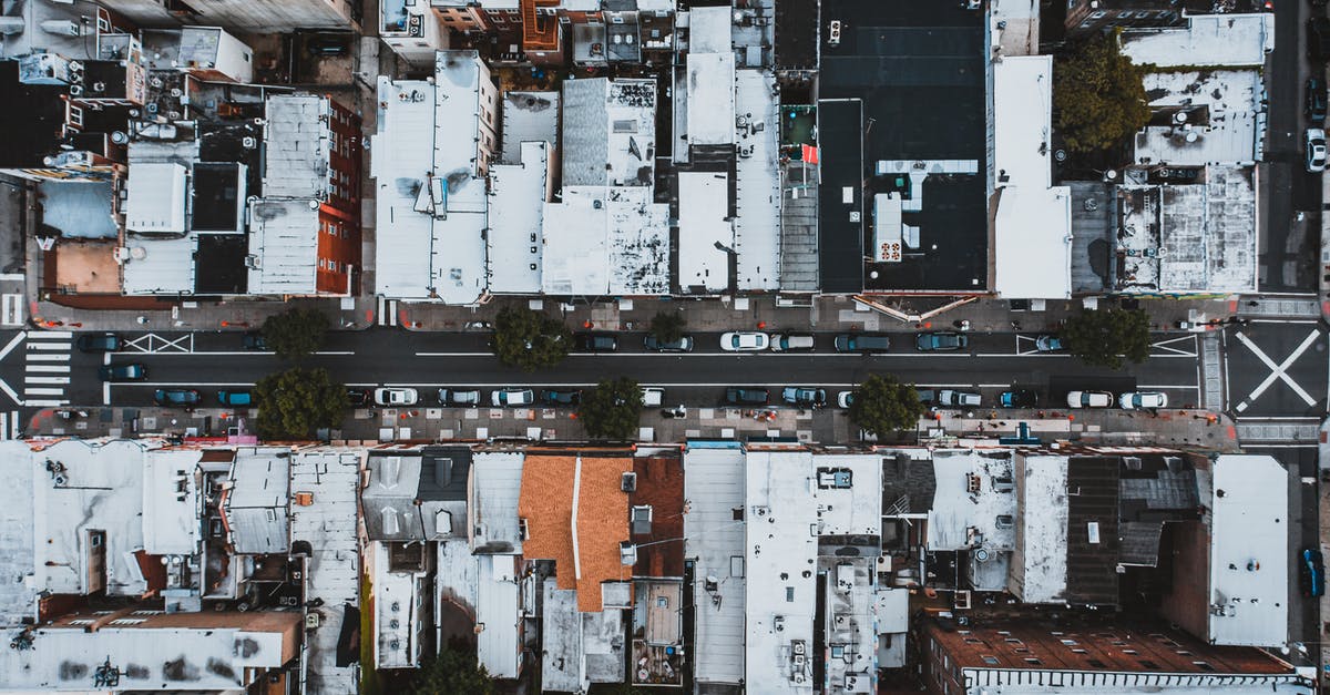 How can I move this structure up one block? - Aerial view of cars moving on city street surrounded by houses with white roofs in residential district