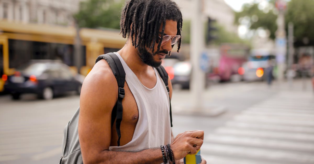 How can I open the Stellaris Console? - Confident adult Hispanic male traveler in sunglasses and casual clothes with backpack opening can of drink while walking along pavement against blurred cars driving along street and empty crosswalk in downtown