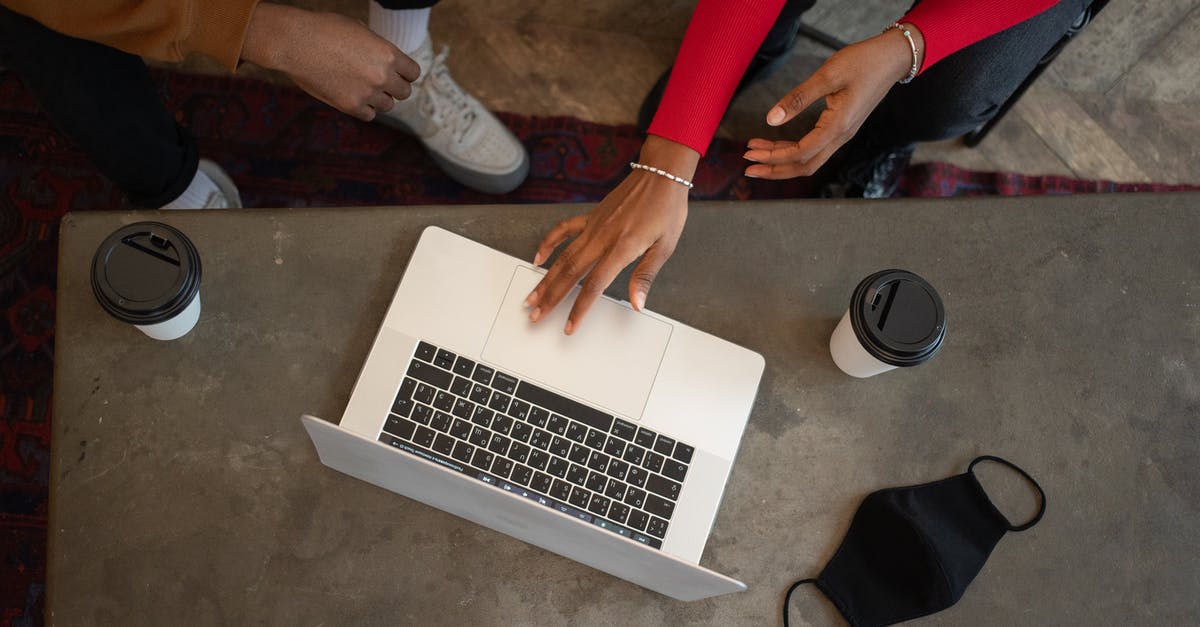 How can I prevent enemies from going through doors aboard my ship? - Top view of crop anonymous African American coworkers surfing netbook while sitting at table with medical mask and takeaway cups of coffee during work