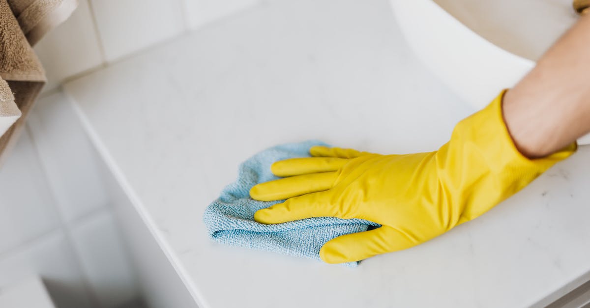 How can I remove Endermen from the game? - From above crop unrecognizable person with microfiber cloth wearing yellow rubber glove and cleaning white marble tabletop of vanity table with washbasin in bathroom