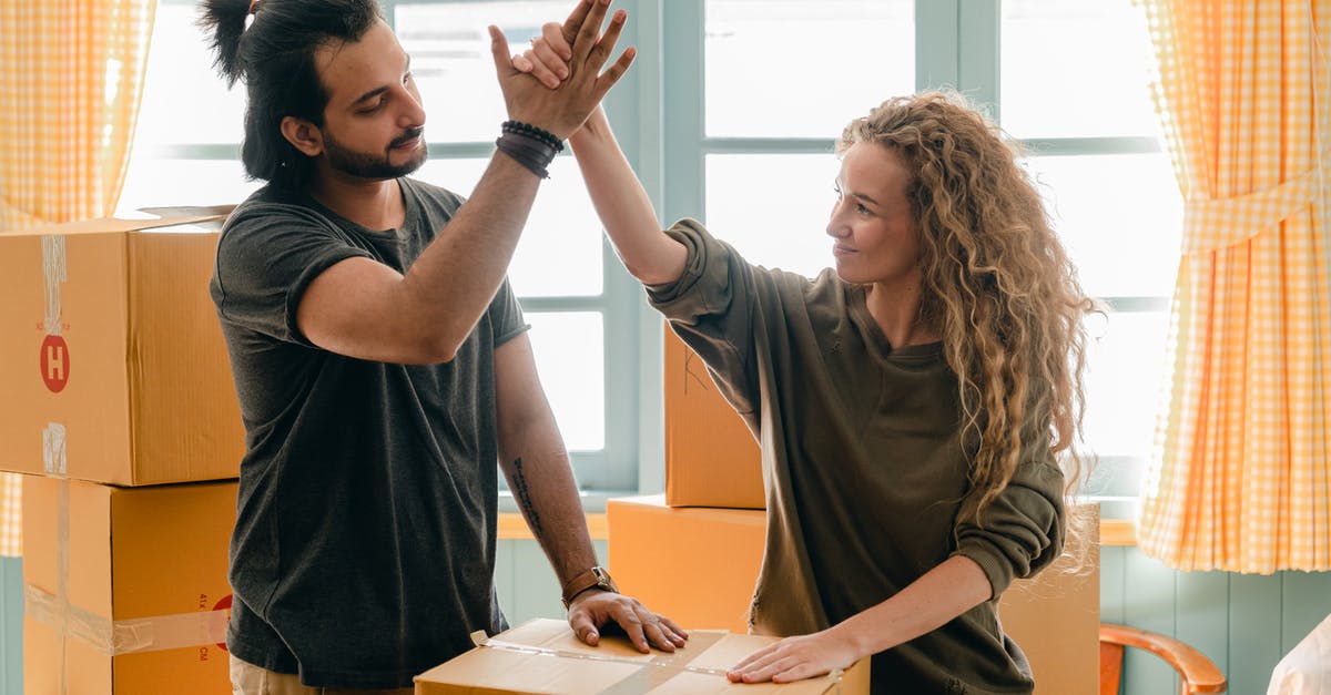 How can I spawn a falling block moving toward where I'm looking? - Happy woman in casual wear standing near heap of cardboard boxes and giving high five to ethnic boyfriend with ponytail showing agreement while looking at each other