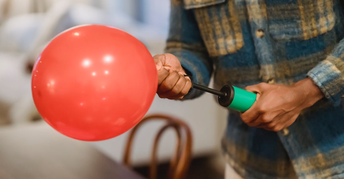How can I switch between automatic and manual air combat? - Faceless ethnic guy using manual air inflator while blowing balloons at home