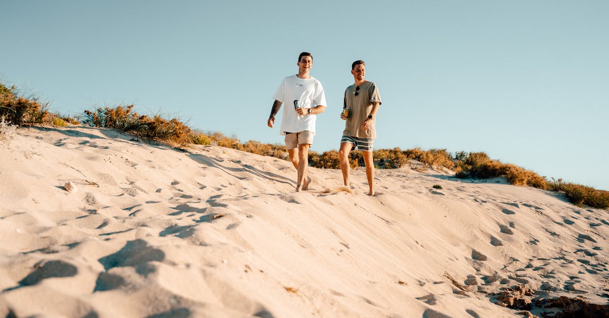 How can I tell if it's day or night when I can't see the sun? - Man and Woman Walking on White Sand