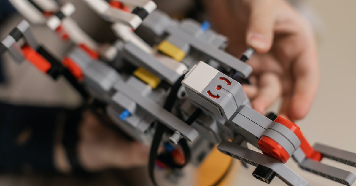 How can I unlock new components? - From above of crop unrecognizable man assembling modern robot constructor at home in daylight