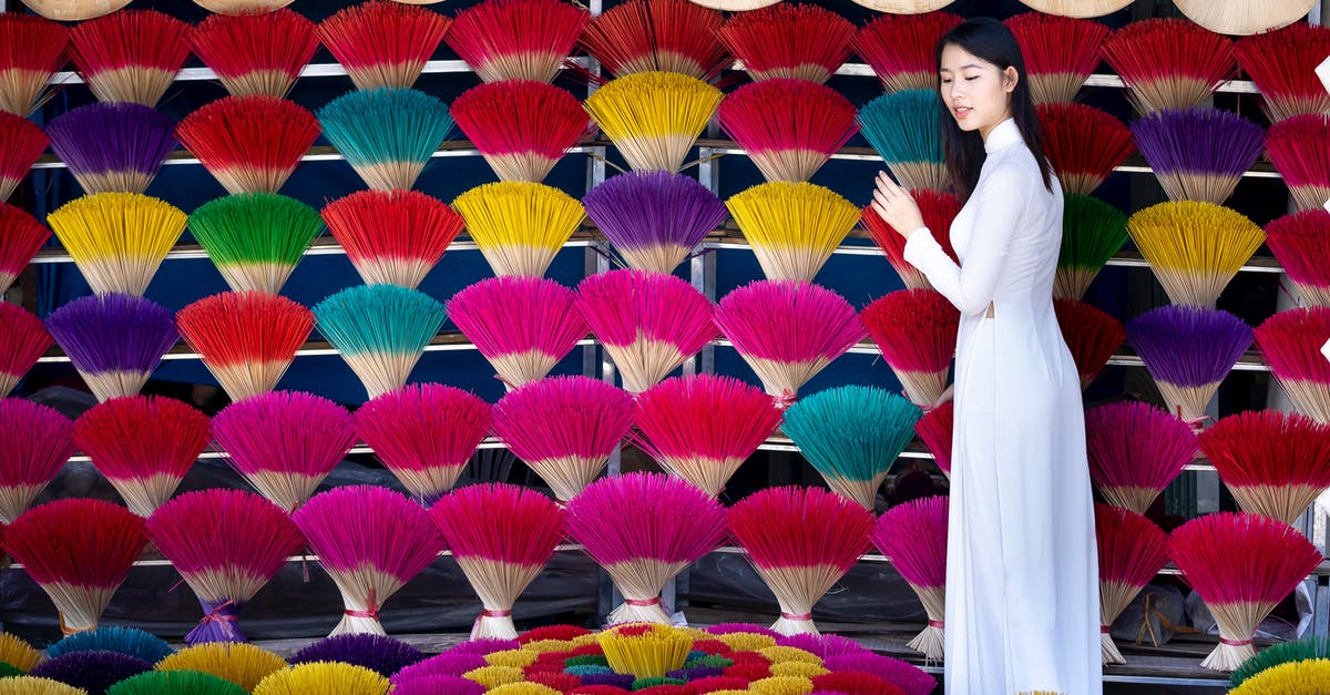 How can I view the content of a USB stick on a PS4? - Side view of charming Asian female in white dress standing near collection of multicolored incense sticks and collection of traditional hats