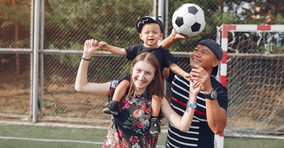 How can I walk automatically in games that don't support it? - Positive smiling diverse parents giving piggyback ride to adorable toddler son while spending weekend together with football ball on sports ground on sunny day