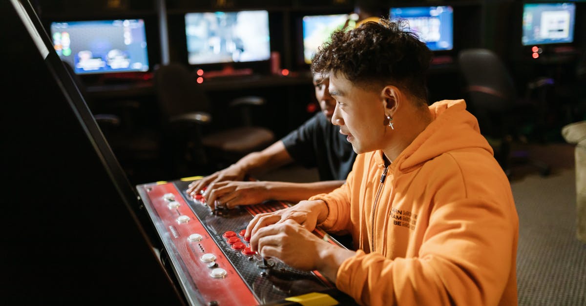 How can modern Arcade machines have thousands of games while the originals could only hold one? - Two Men Playing an Arcade Video Game How can modern Arcade machines have thousands of games while the originals could only hold one? - Two Men Playing an Arcade Video Game