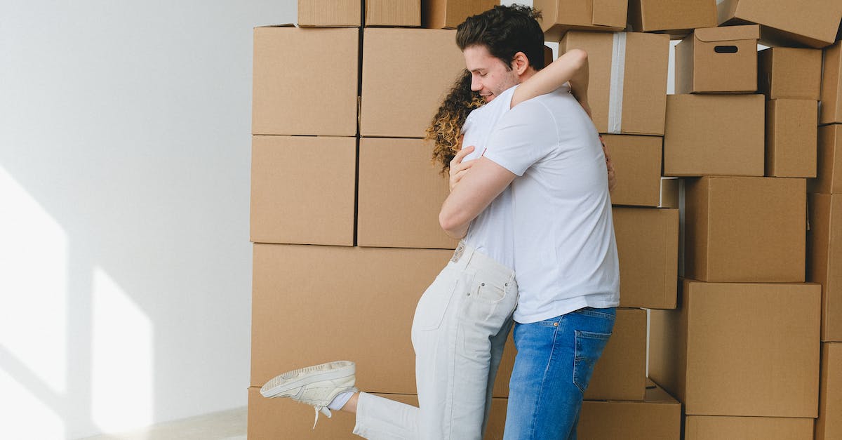 How close can villagers move to your house? - Cheerful couple hugging near carton boxes during relocation in new apartment