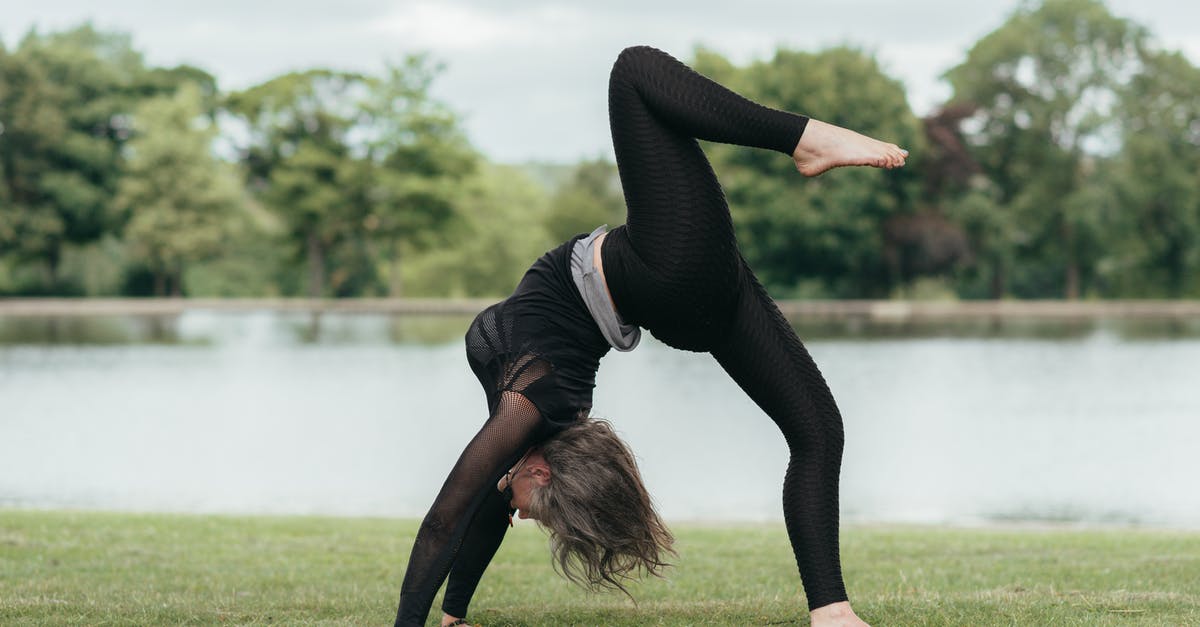How could one grow in rank in TFX? - Side view of anonymous flexible female standing in Eka Pada Urdhva Dhanurasana pose while practicing yoga on river shore