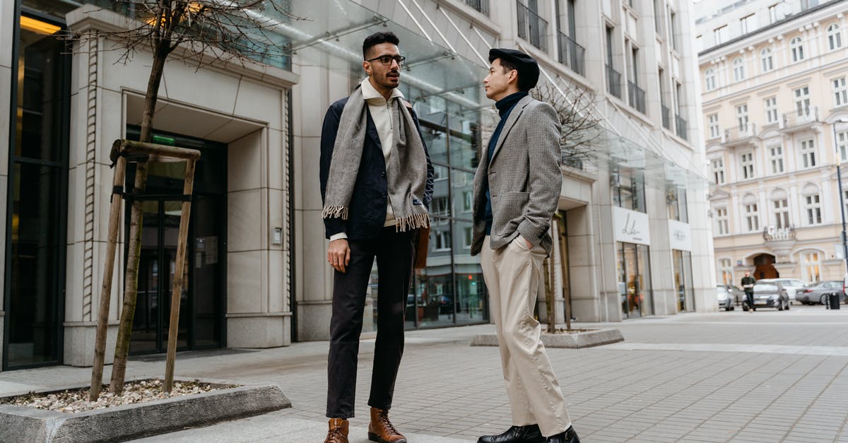 How do I acquire Outfit Vouchers? - Man in Gray Coat Standing Beside Man in Gray Coat