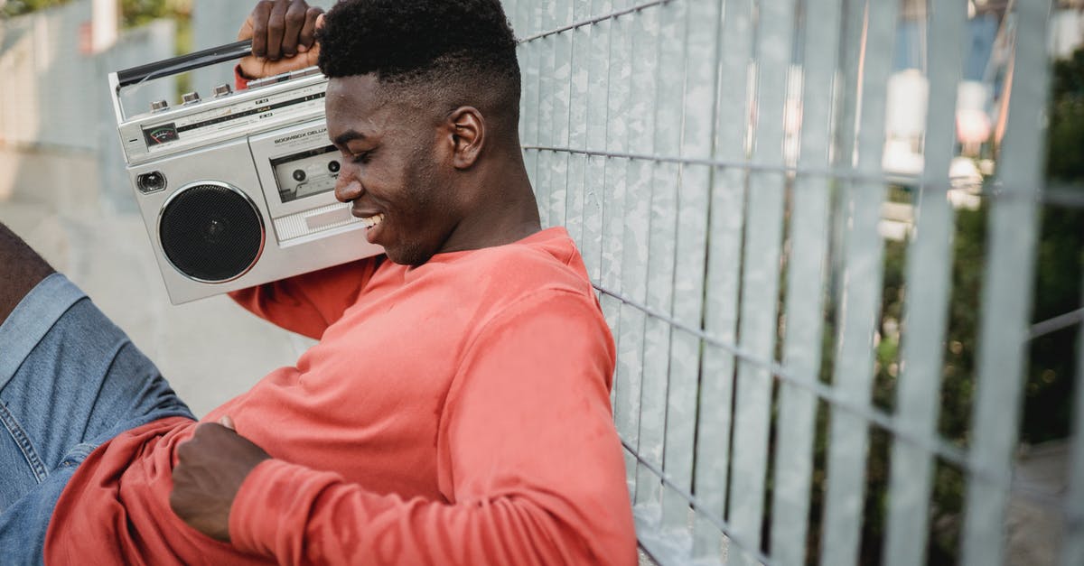 How do I add songs to the Radio? - Smiling black man enjoying music from old tape recorder outdoors