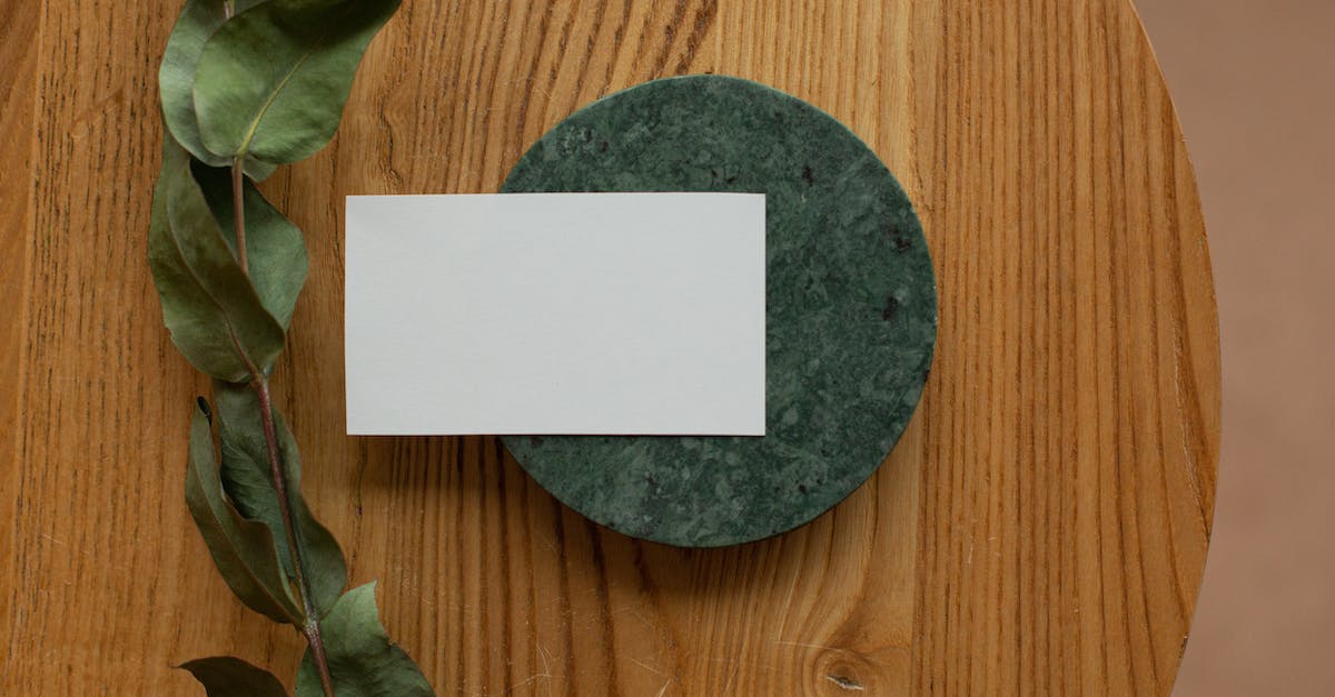 How do I apply a new card back? - Top view of white mock up business card on round board placed on wooden table with green branch in room