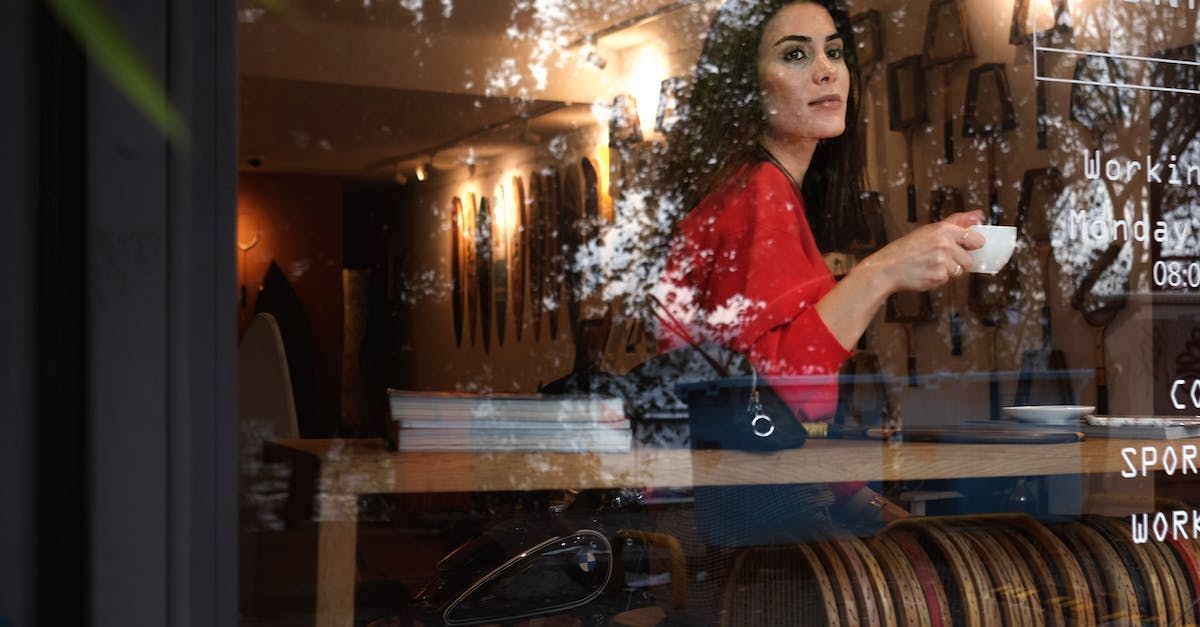 How do I break formation - Through glass of female in stylish red clothes drinking coffee from white cup while looking out window in modern cafeteria How do I break formation - Through glass of female in stylish red clothes drinking coffee from white cup while looking out window in modern cafeteria