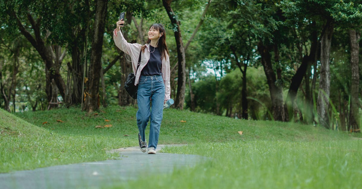 How do I break sturdy-looking rocks? - Smiling young Asian woman talking via smartphone while walking in park