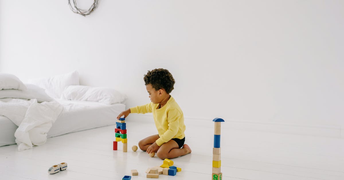 How do I build a child's bedroom? - A Boy Playing with Wooden Toys on the White Floor