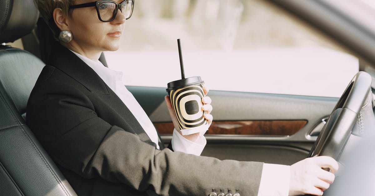 How do I check where to go next? - Stylish woman with takeaway coffee driving car How do I check where to go next? - Stylish woman with takeaway coffee driving car