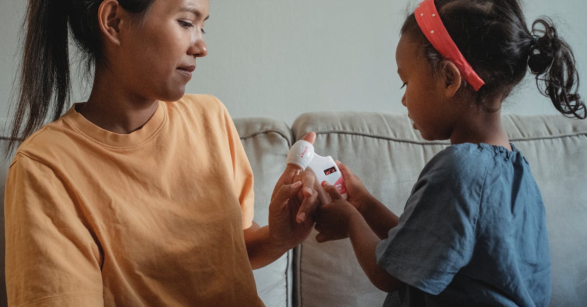 How do I check which version of the game it is that I have? - Side view of little girl checking pulse with toy heart rate monitor on finger of ethnic mother while playing game