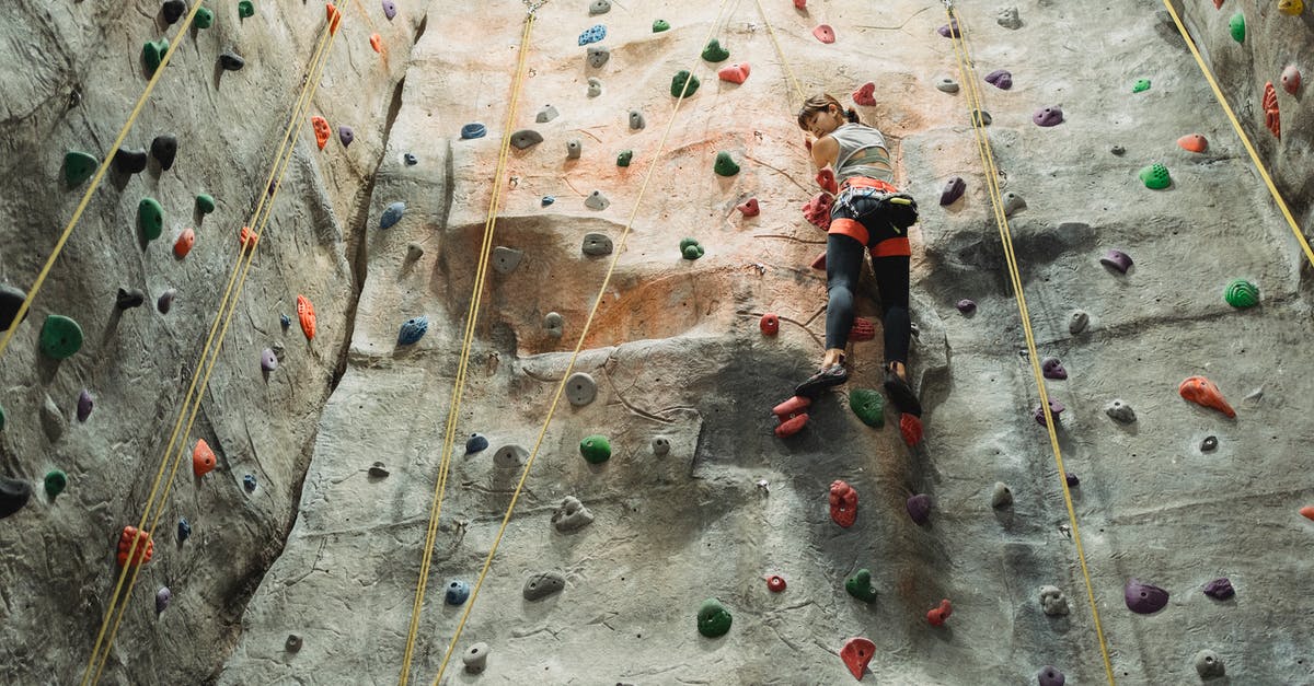 How do I climb down from the hideout in Firewatch? - From below back view of young ethnic female athlete climbing artificial rock with holds while looking down