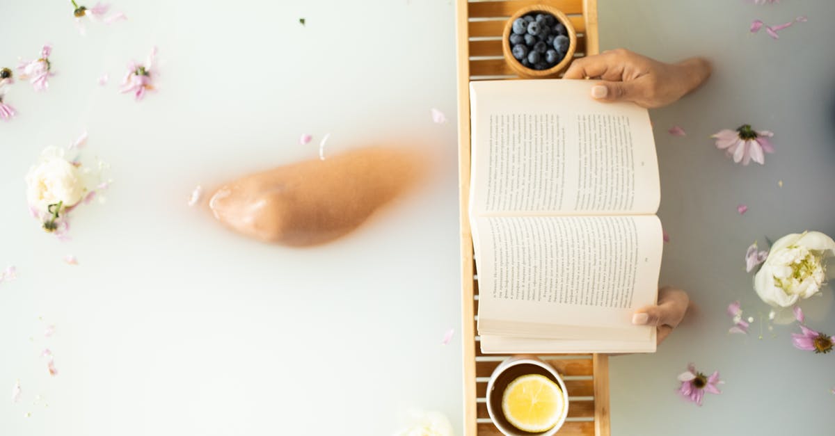 How do I collect milk from cows in Dragon Quest Builders 2? - Top view of crop unrecognizable lady in white water in bathtub with fresh colorful flower petals with wooden tray with cup of tea with lemon and blueberries while reading book