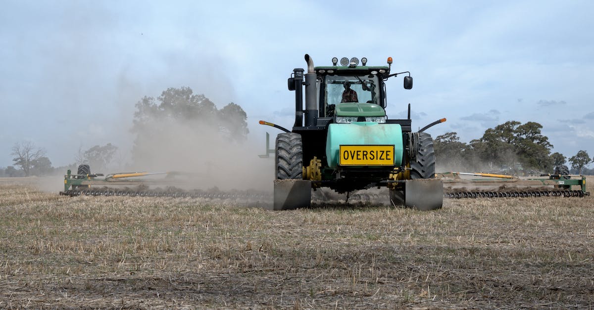 How do I combine my Equipment? - Tractor plowing agricultural field near green trees located under blue sky in summer day