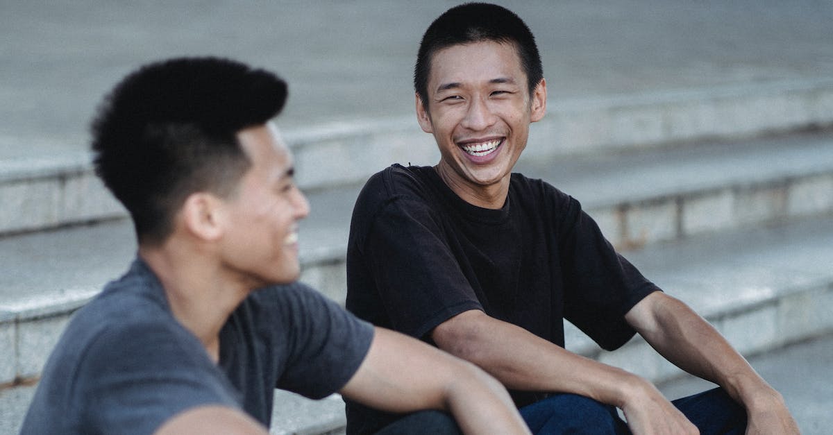 How do I connect with my friend in Minecraft Mac - Cheerful Asian male friends in casual wear with dark hair smiling while sitting on stone stairs on street in city